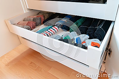 Many colorful men`s socks in a plain white wooden sock drawer Stock Photo