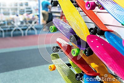 Many colorful plastic small skateboards toys hanged on store shop window display. Child sport and fun accessories. Children gift Stock Photo