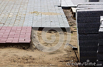 many curbs for construction works on pallets at the site laying paving slabs city square and laid tiles on a layer of sand Stock Photo