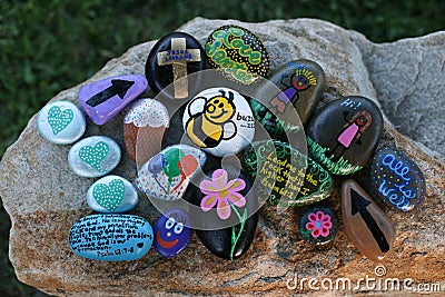 Many decorated painted rocks displayed on a small boulder Stock Photo