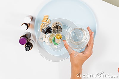 Many dietary supplements tablets and glass of water for daily pills intake on white background. Set of mulvitamin, amino Stock Photo