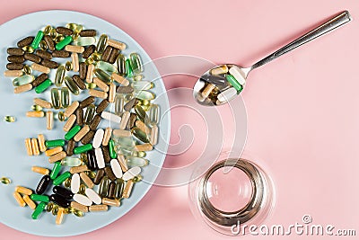 Many dietary supplements tablets, glass of water and spoon for daily pills intake on pink background. Set of zinc pills Stock Photo