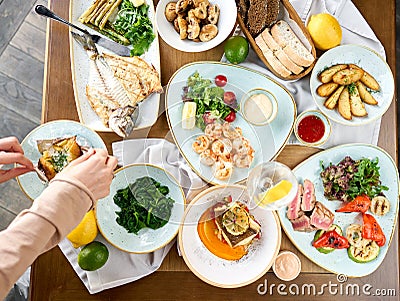Many different delicious dishes dishes on the table. Various snacks and antipasti on the table. Plates seafood BBQ with Stock Photo