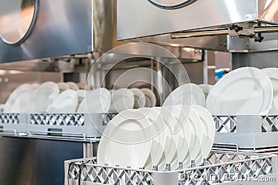 Many dish or white plate arranged on basket for cleaning by automatic dishwasher machine in kitchen room restaurant Stock Photo