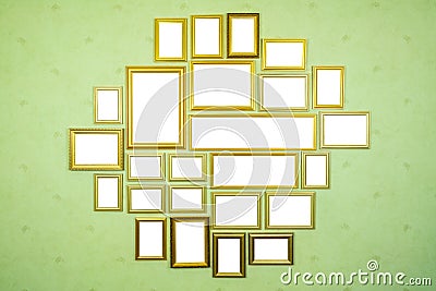 Many empty golden wooden frames with copy space on green wall. Stock Photo