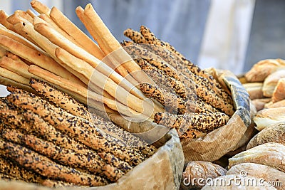 many fresh bread sticks with salt and seeds in paper bags and other bakery around. degustation of bread. Catering and Stock Photo