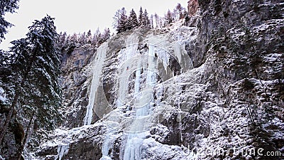 Many frozen waterfalls with extreme ice climbers on them on a cold winter day in the Dolomites in Italy Stock Photo