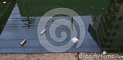 Many garbage, plastic bottles, plastic bags, leaves, food scraps and paper floating in river or canal Editorial Stock Photo