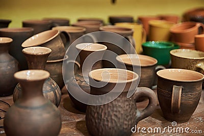 Many handmade clay jugs on shelf in workshop Stock Photo