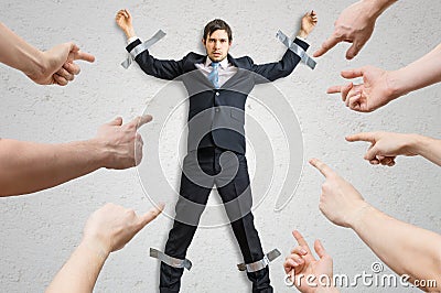 Many hands blame employee who is taped to the wall Stock Photo