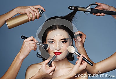 Many hands with cosmetics brush, shadows doing make up Stock Photo