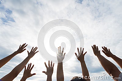 Many hands raised up against the blue sky. Friendship Stock Photo