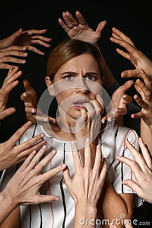 Many hands stretched to woman on dark background. Panic attack Stock Photo