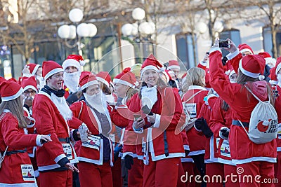 Many happy Santas in traditional red dresses and beard in the St Editorial Stock Photo