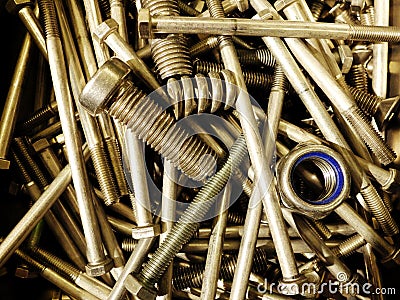 Many iron fasteners laying on top of each other with a big bolt at the front in a pile Stock Photo