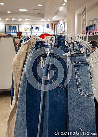 Many jeans hanging on a rack. Row of pants denim jeans hanging in closet. Jeans on the hangers on a sale Editorial Stock Photo