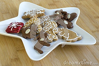 Many kinds of Christmas cookies on white plate, gingerbread dark and light, star shape dish, bamboo wooden background Stock Photo