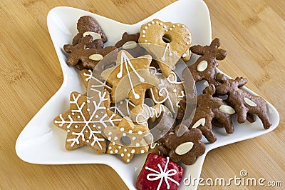 Many kinds of Christmas cookies on white plate, gingerbread dark and light, star shape dish, bamboo wooden background Stock Photo