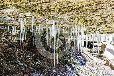 Many long white icicles hanging from a rocky overhang, red rocks Stock Photo