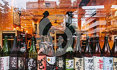 Many major and minor brands of Japanese liquors are including beer, sake, spirits and umeshu in front glass window. Editorial Stock Photo