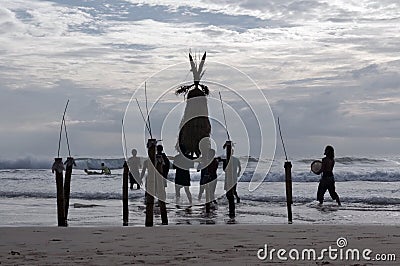 Many men carry the Straw Scarecrow into the water during a ceremony for good weather and good fishing, at sunset Editorial Stock Photo