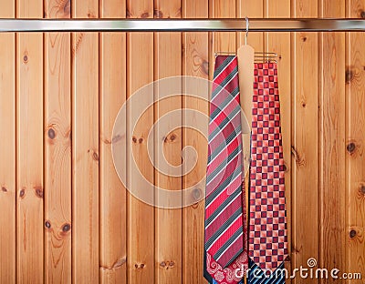 Many mens ties hanging on the rack. Wooden background Stock Photo
