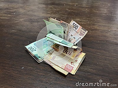 Many mixed mexican peso bills spread over a wooden desk Stock Photo