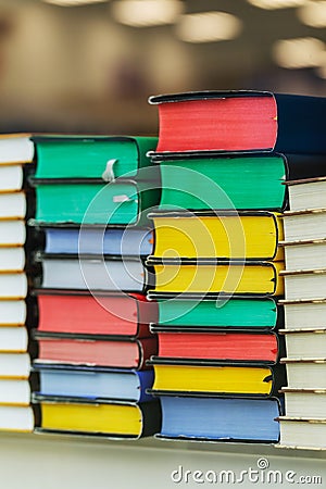 Many multi-colored books are stacked on top of each other in the glass showcase of a bookstore. Collection of old books Stock Photo