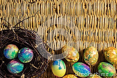 Many multi-colored Easter eggs. Three eggs lie in a nest of branches. The rest of the Easter eggs lie on the background of a table Stock Photo