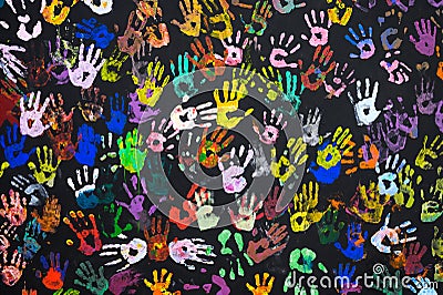 Many multi-colored prints of human hands on a black background. Stock Photo