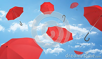 Many open red umbrellas falling from the blue sky dotted with clouds. Stock Photo
