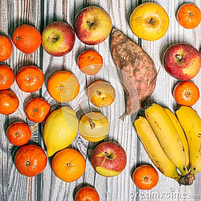 Many orange autumn fruits like mandarins, apples, pears and bananas on a wooden surface Stock Photo