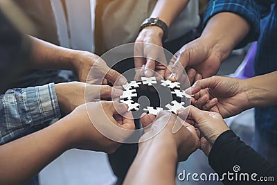 Many people hands holding a jigsaw puzzle in circle together Stock Photo