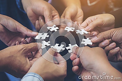 Many people hands holding a jigsaw puzzle in circle together Stock Photo