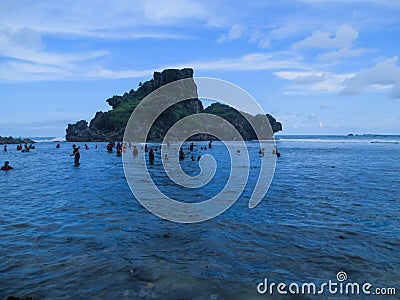 Many people swim on Nglambor beach with a small island view Editorial Stock Photo