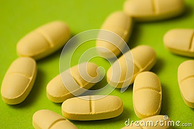 Many pills, antibiotics or vitamins yellow color on a green background close-up, close-up Stock Photo