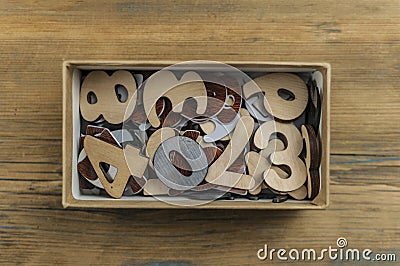 many random arabic numerals in a cardboard box on wooden table. Top view Stock Photo