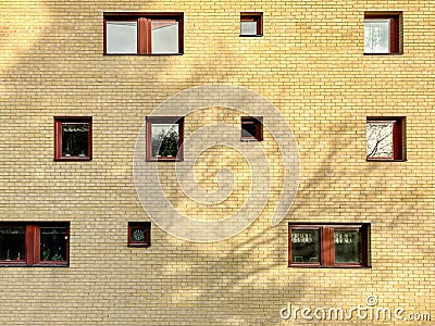 Many random placed windows on a yellow brick residential building outdoors. Stock Photo