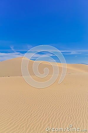 Many ripples wave lead to peak of sand dunes under sunny blue cloud sky in Nam Cuong, Phan Rang, Viet Nam. Stock Photo