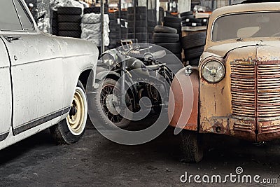 Many rusty abandoned forgotten antique oldtimer old car and motorcycles at junkyard factory storage warehouse indoors Editorial Stock Photo