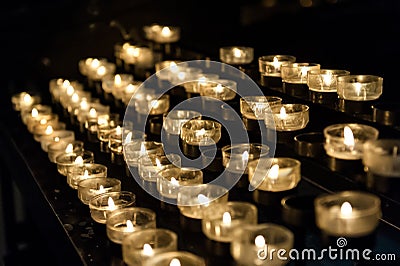 Many small candles in the church lightning in the dark Stock Photo