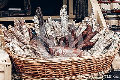 many smoked sausages and salami in wooden basket on table at street food festival. catering outdoors, open kitchen, summer picnic Stock Photo