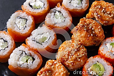 Many sushi , set of Japanese rolls Philadelphia with salmon, California with caviar, baked with eel and cheese , on a black Stock Photo