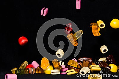 Many sweet and colourful candies are falling down to the table Editorial Stock Photo