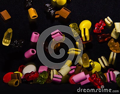 Many sweet and colourful candies are falling down to the table Editorial Stock Photo