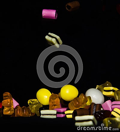Many sweet and colourful candies are falling down to the table Editorial Stock Photo