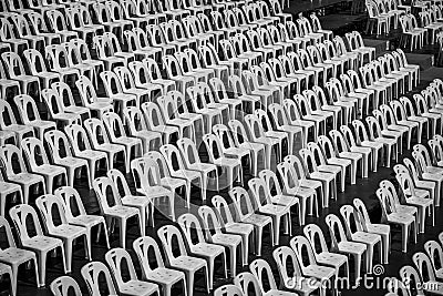 Many white plastic chairs in rows with black and white tone. Stock Photo