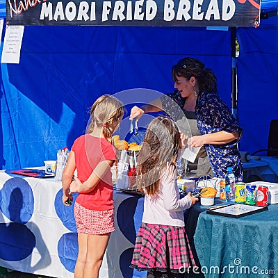 Maori fried bread being prepared for two young customers by a cheerful market stall holder, New Zealand Editorial Stock Photo