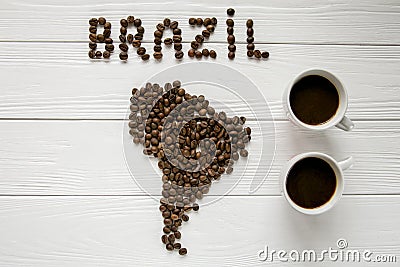 Map of the Brazil made of roasted coffee beans laying on white wooden textured background two cups of coffee Stock Photo
