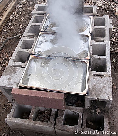 Maple sap concentrations boiling down to sweet homemade syrup in backyard evaporator Stock Photo